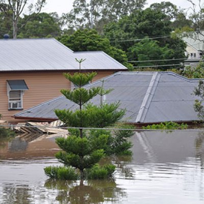 Floods inundating several homes with only the roof tiles visible of the one in the centre of the picture 